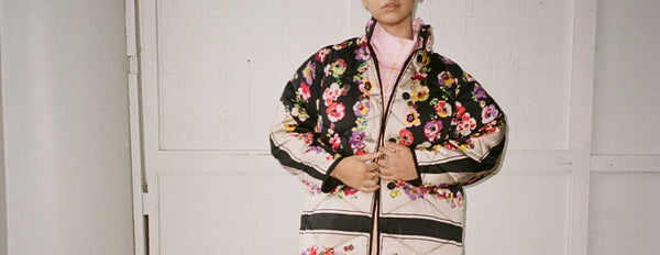 Model wearing a floral coat in front of a white wall