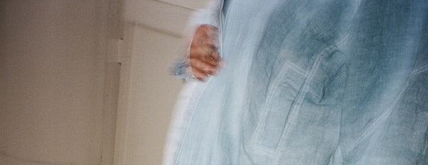 Hand on a denim coat in front of a white wall